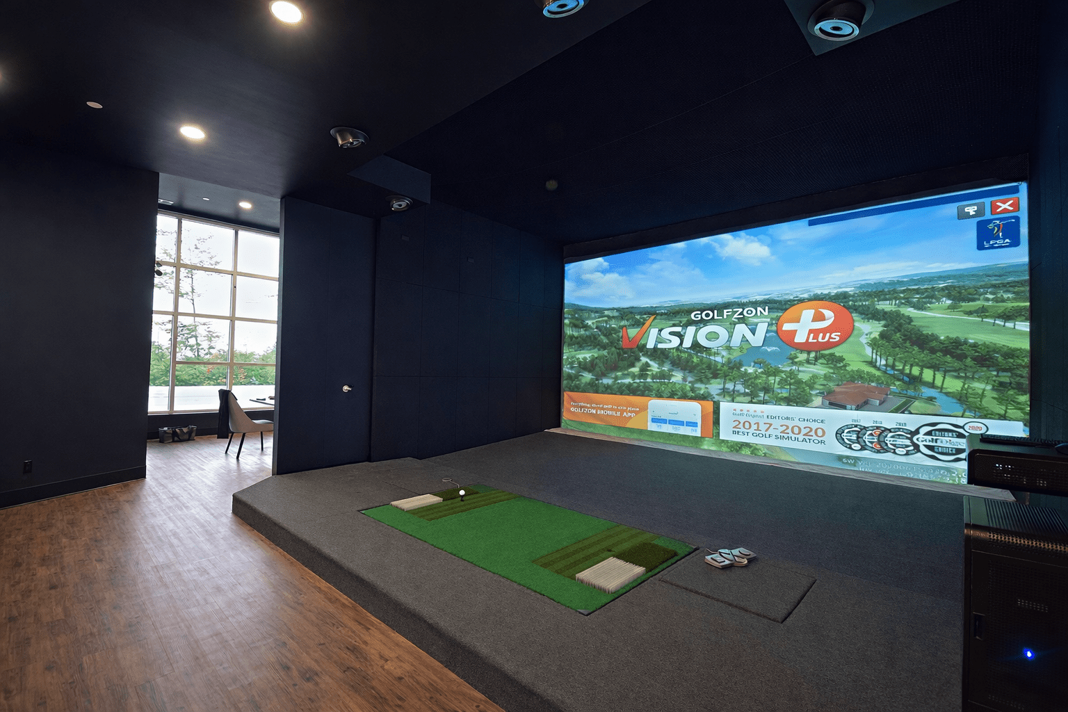 Indoor golf simulator room construction in Toronto featuring projection screen, acoustic wall panels, hitting platform, and custom entertainment build-out