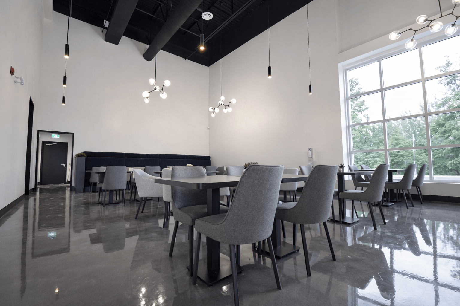 Open dining and seating area construction with polished concrete floors, modern lighting fixtures, and high ceilings in a Toronto commercial space