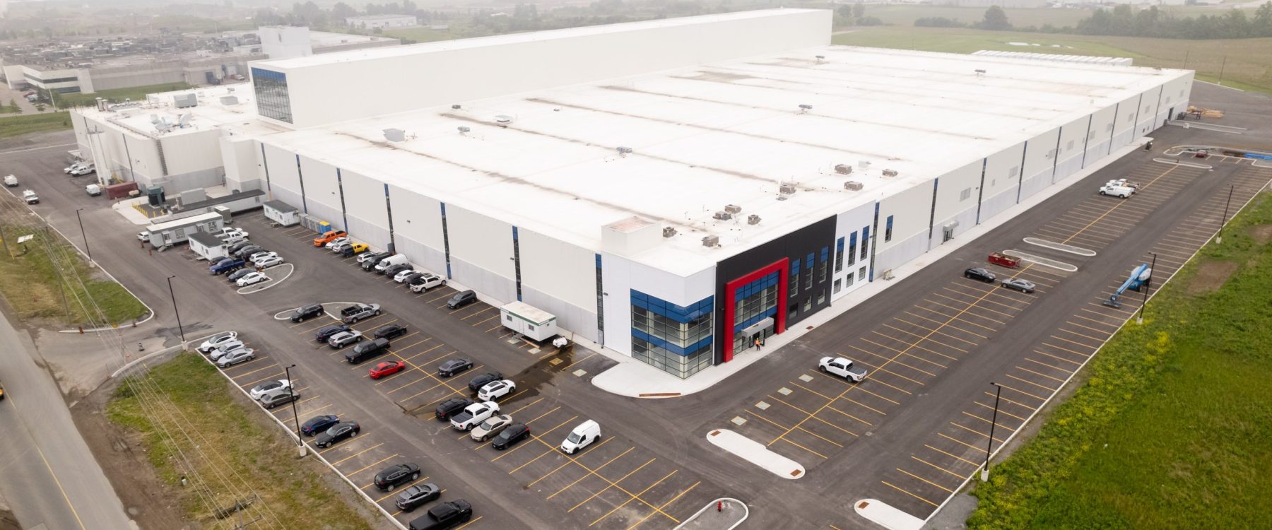 Side angle image of Atlantic Packaging’s extensive facility, emphasizing the strategic layout of parking spaces, loading docks, and a streamlined industrial building structure.
