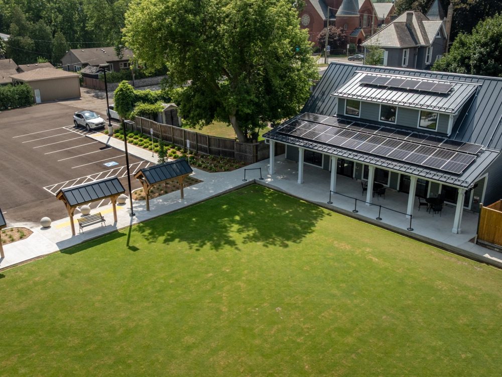 Wilkin Family Community Centre in Paris, Ontario, constructed by GTA General Contractors. The modern net-zero building features solar panels on a pitched roof, a covered patio with seating, landscaped parking, and a large green lawn, blending sustainability with community use.