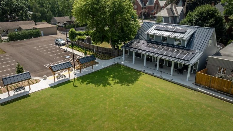 Wilkin Family Community Centre in Paris, Ontario, constructed by GTA General Contractors. The modern net-zero building features solar panels on a pitched roof, a covered patio with seating, landscaped parking, and a large green lawn, blending sustainability with community use.