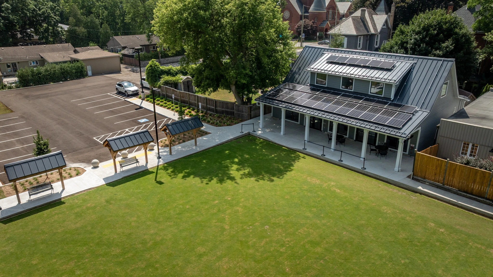 Wilkin Family Community Centre in Paris, Ontario, constructed by GTA General Contractors. The modern net-zero building features solar panels on a pitched roof, a covered patio with seating, landscaped parking, and a large green lawn, blending sustainability with community use.