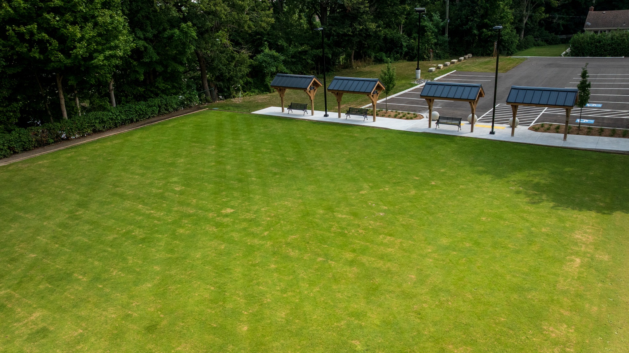 Wilkin Family Community Centre in Paris, Ontario, constructed by GTA General Contractors. The modern net-zero building features solar panels on a pitched roof, a covered patio with seating, landscaped parking, and a large green lawn, blending sustainability with community use.