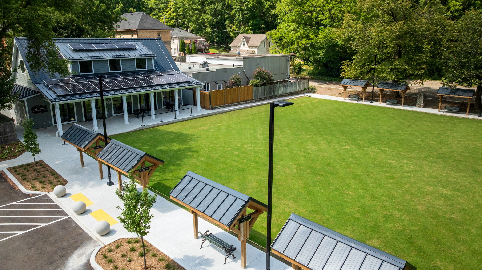 Wilkin Family Community Centre in Paris, Ontario, constructed by GTA General Contractors. The modern net-zero building features solar panels on a pitched roof, a covered patio with seating, landscaped parking, and a large green lawn, blending sustainability with community use.