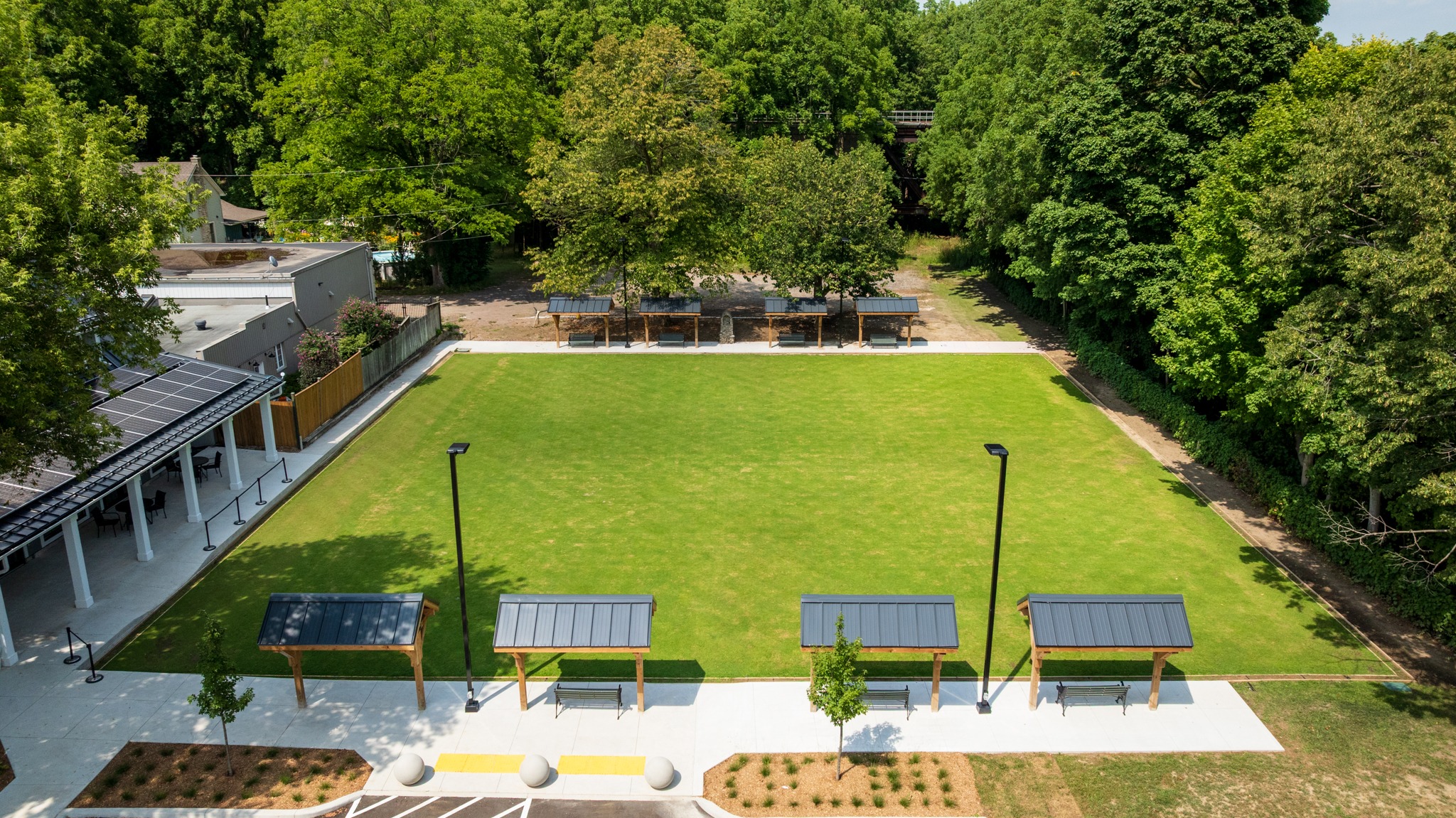 Wilkin Family Community Centre in Paris, Ontario, constructed by GTA General Contractors. The modern net-zero building features solar panels on a pitched roof, a covered patio with seating, landscaped parking, and a large green lawn, blending sustainability with community use.