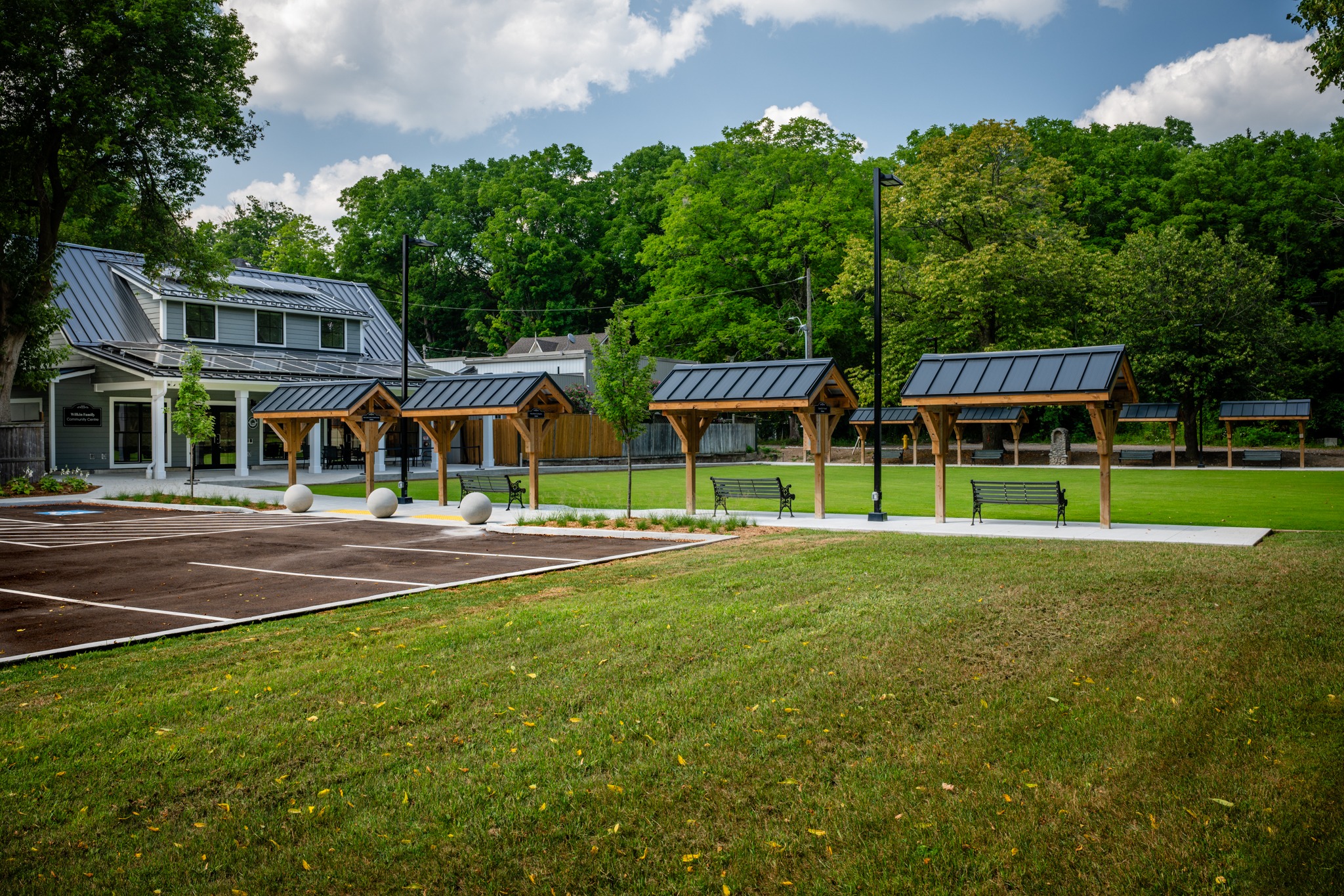 Wilkin Family Community Centre in Paris, Ontario, constructed by GTA General Contractors. The modern net-zero building features solar panels on a pitched roof, a covered patio with seating, landscaped parking, and a large green lawn, blending sustainability with community use.
