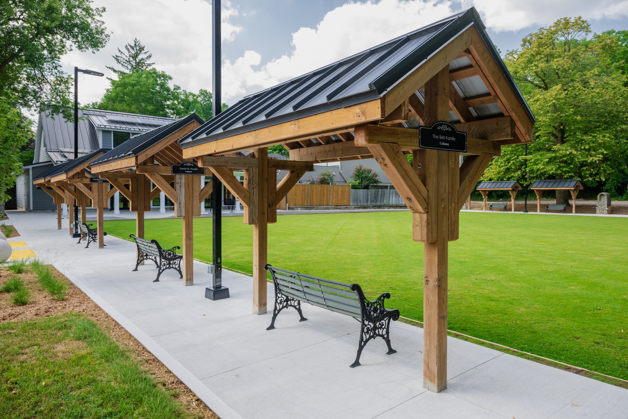 Wilkin Family Community Centre in Paris, Ontario, constructed by GTA General Contractors. The modern net-zero building features solar panels on a pitched roof, a covered patio with seating, landscaped parking, and a large green lawn, blending sustainability with community use.