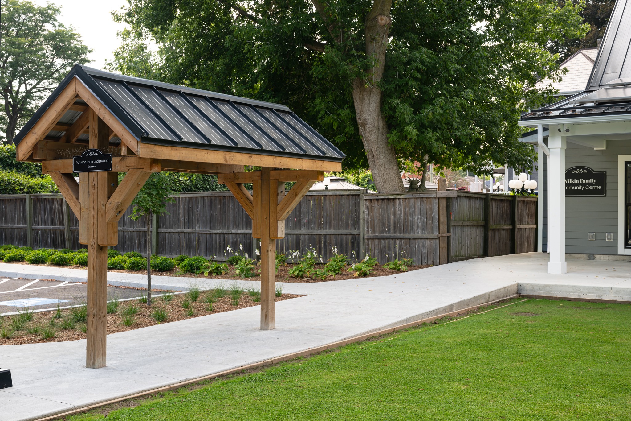 Wilkin Family Community Centre in Paris, Ontario, constructed by GTA General Contractors. The modern net-zero building features solar panels on a pitched roof, a covered patio with seating, landscaped parking, and a large green lawn, blending sustainability with community use.
