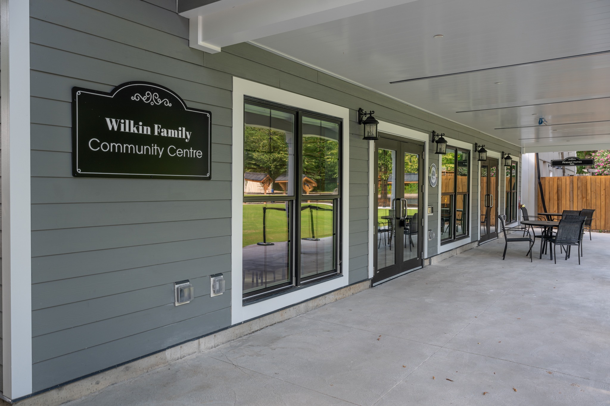 Wilkin Family Community Centre in Paris, Ontario, constructed by GTA General Contractors. The modern net-zero building features solar panels on a pitched roof, a covered patio with seating, landscaped parking, and a large green lawn, blending sustainability with community use.