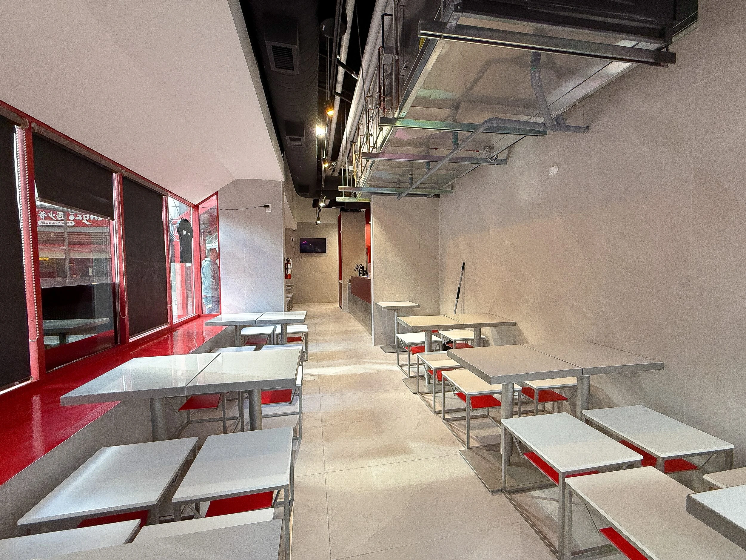 Commercial restaurant construction with open dining area, exposed ceiling design, and contemporary red-and-grey interior finishes.