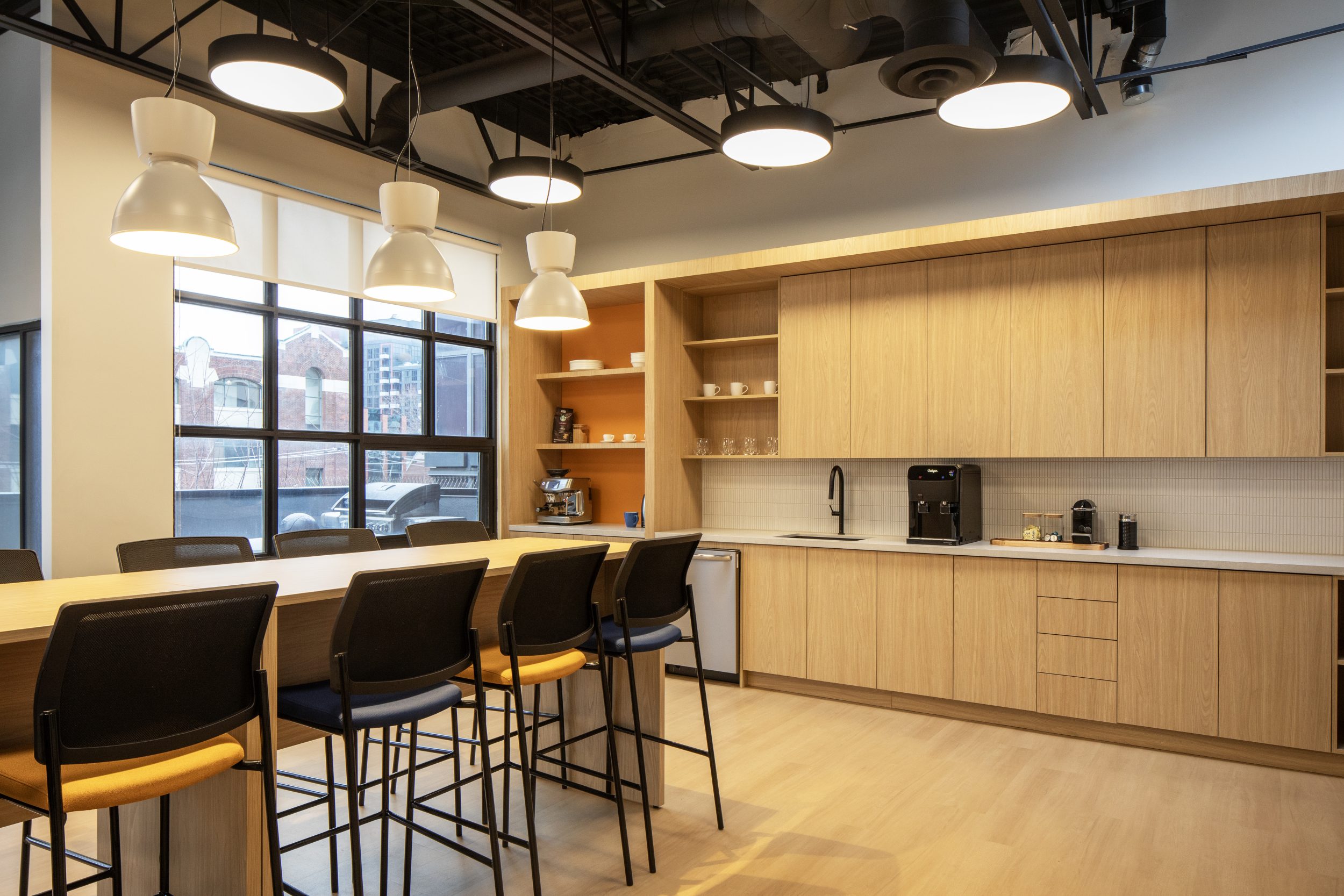 Neoen corporate office construction featuring large kitchen island, pendant lighting, custom cabinetry, and modern office interior design