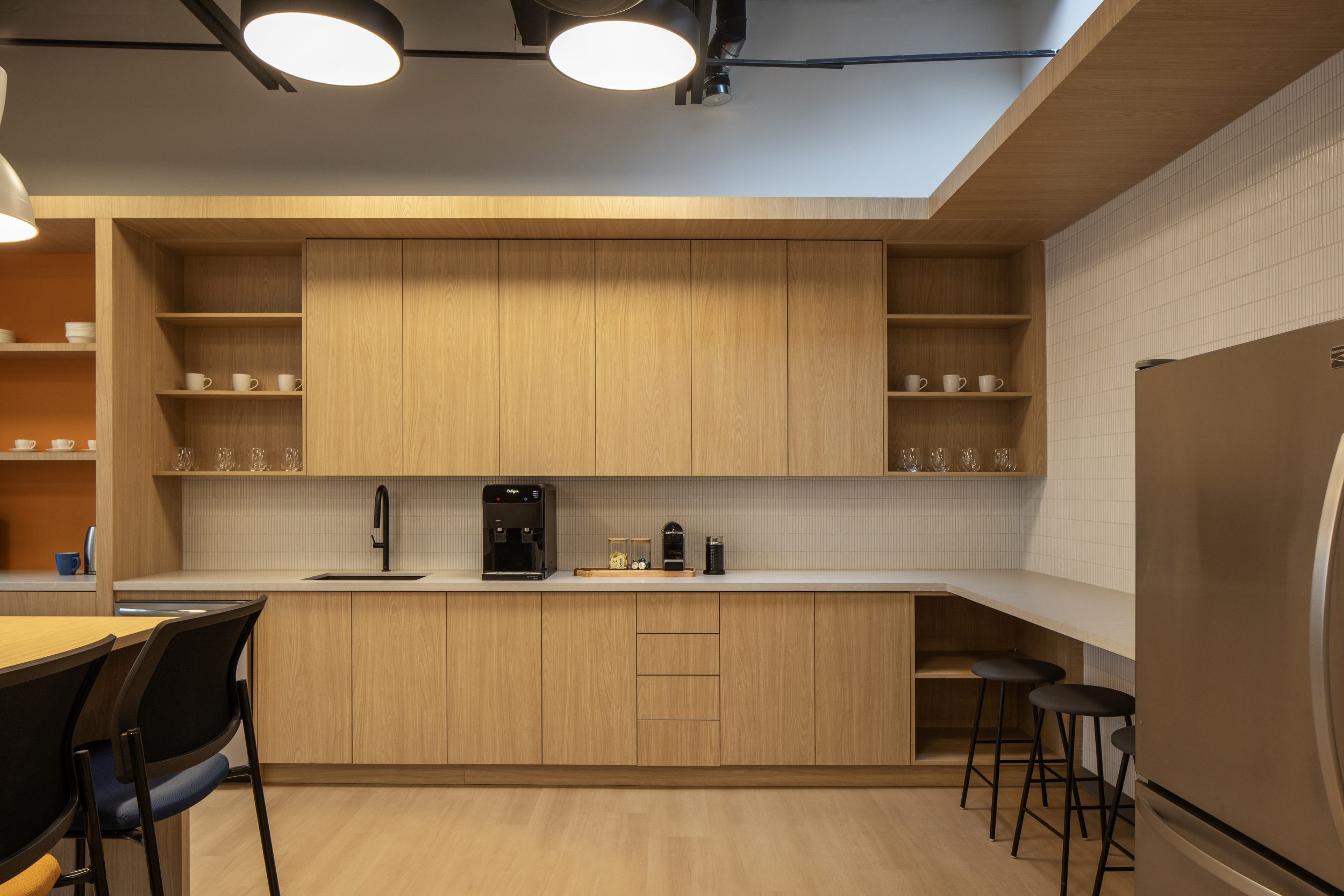 Neoen office construction Toronto showcasing employee breakroom with custom wood finishes, bar seating, and functional workspace design