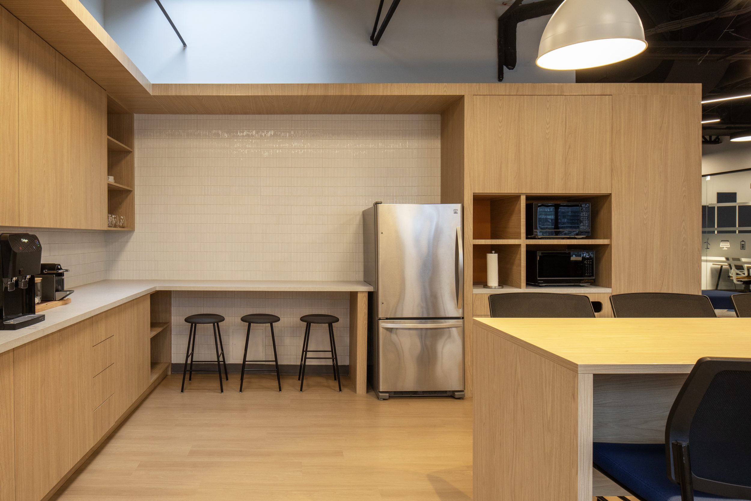 Neoen office build-out featuring modern kitchen area, custom cabinetry, bar seating, and workplace design for employee collaboration