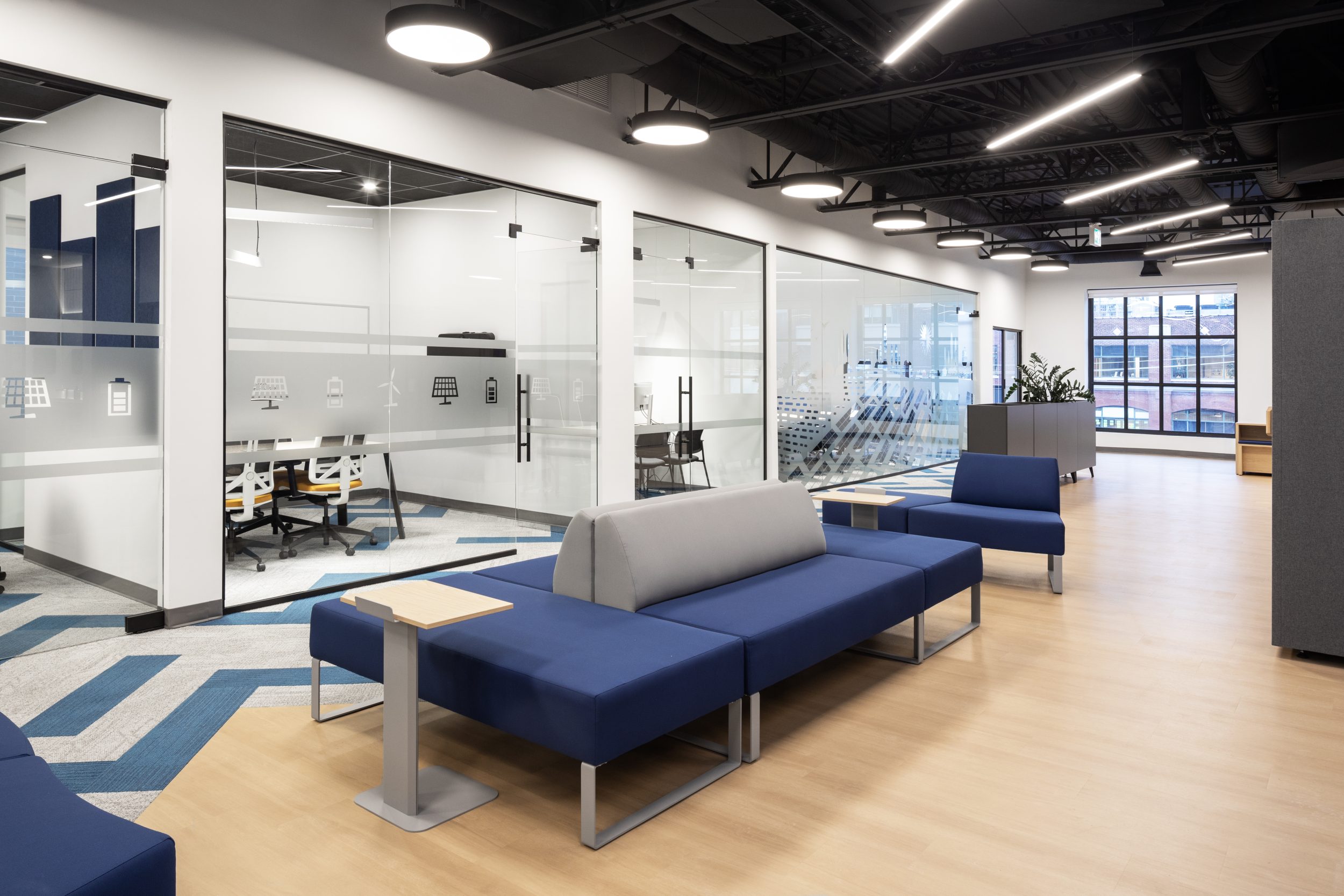 Neoen office build-out Toronto featuring modern lounge seating, glass meeting rooms, open concept layout, and commercial office construction design