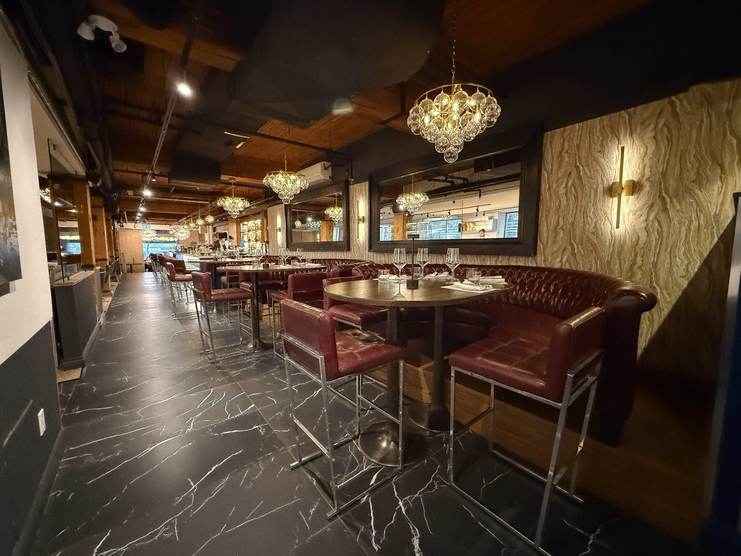 Banquette dining area at BLU Ristorante with tufted leather seating, decorative wall finishes, and ambient chandelier lighting.