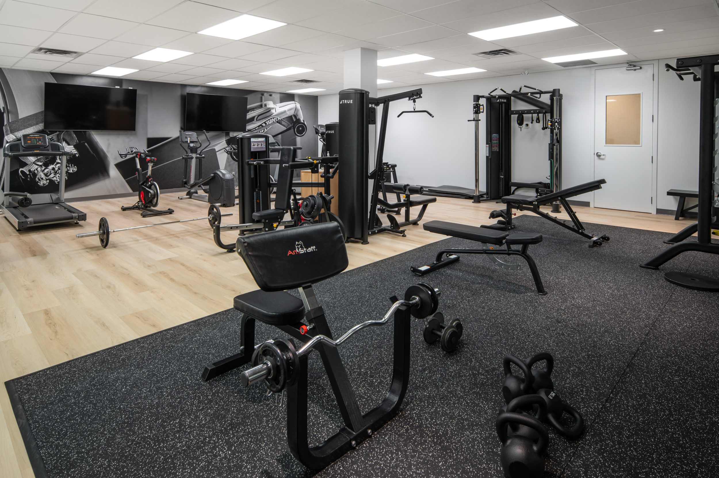 Employee fitness centre at Mattel Canada Headquarters in Mississauga, Ontario featuring commercial gym equipment, strength training stations, cardio equipment, corporate wellness amenities, premium interior finishes, and Design-Build office renovation completed by GTA General Contractors.