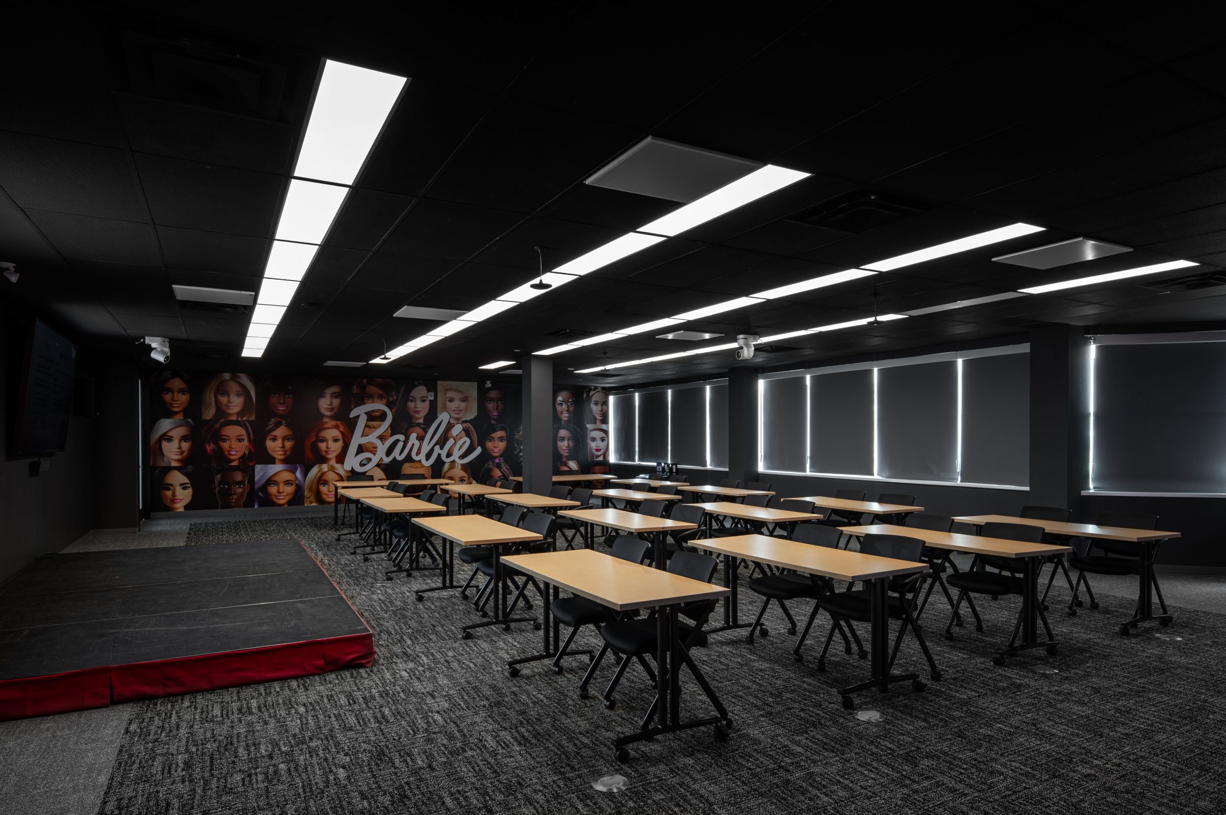 Corporate training centre and employee learning space at Mattel Canada Headquarters in Mississauga, Ontario featuring flexible meeting layouts, presentation stage, integrated AV systems, branded feature graphics, commercial office construction, and Design-Build workplace renovation by GTA General Contractors.