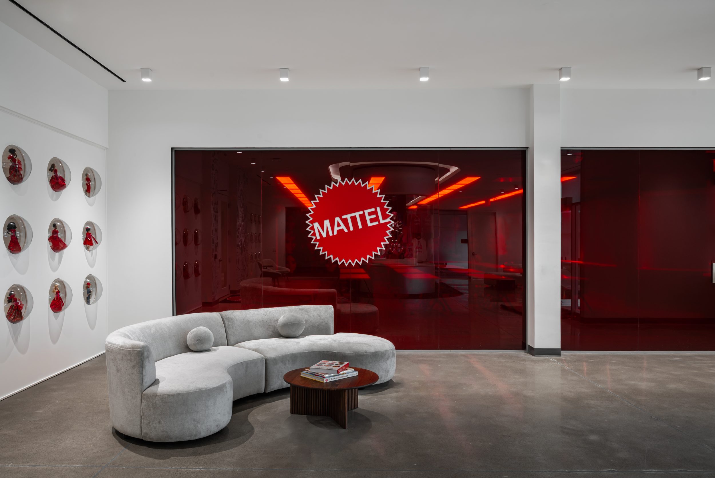 Modern reception lounge at Mattel Canada Headquarters featuring custom seating, branded glass feature wall, architectural lighting, and premium commercial office finishes completed through a Design-Build renovation in Mississauga, Ontario.