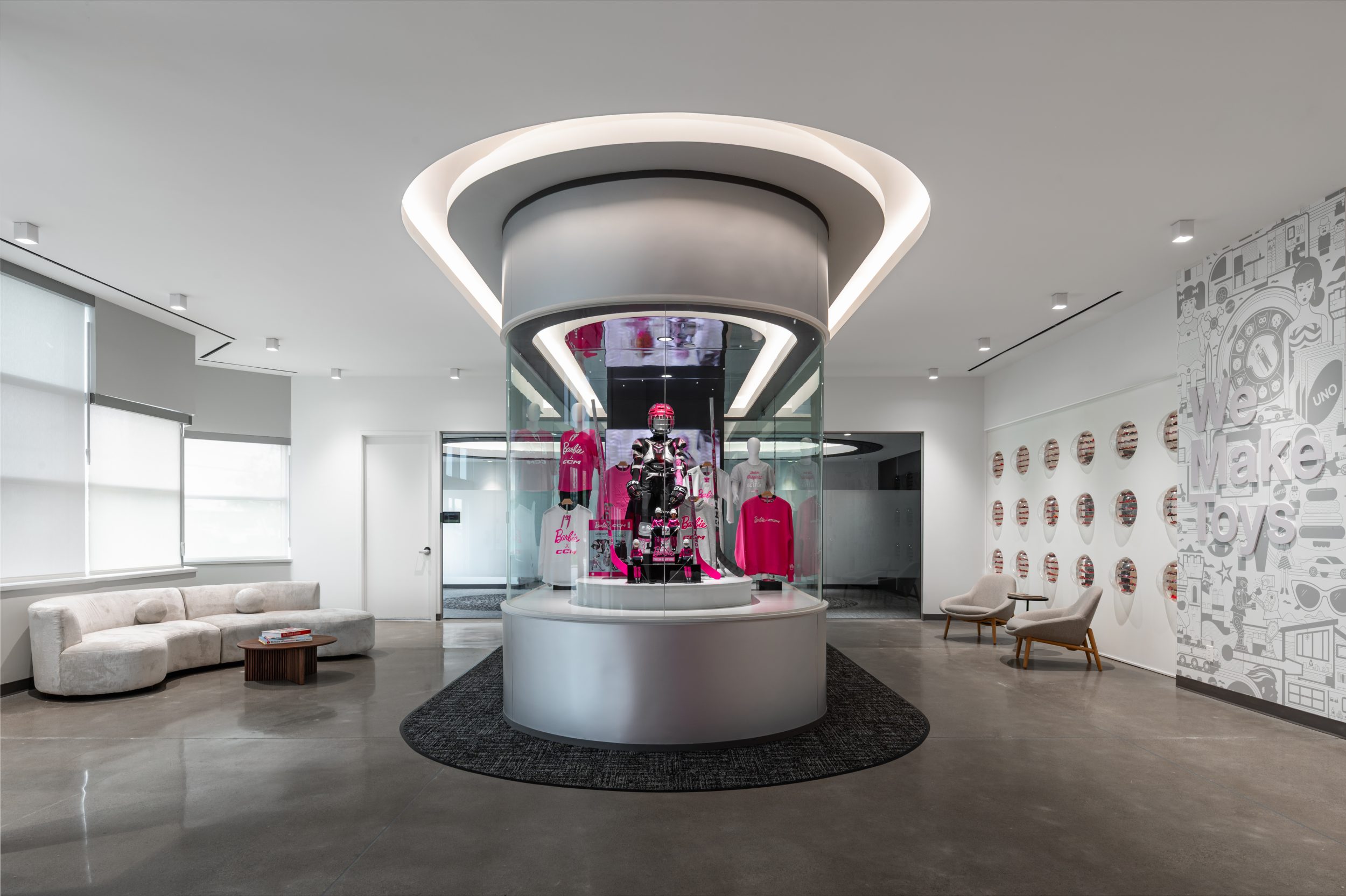 Modern reception lobby at Mattel Canada Headquarters featuring a custom glass display, architectural lighting, branded feature wall, and contemporary commercial office design completed through a Design-Build renovation in Mississauga, Ontario.