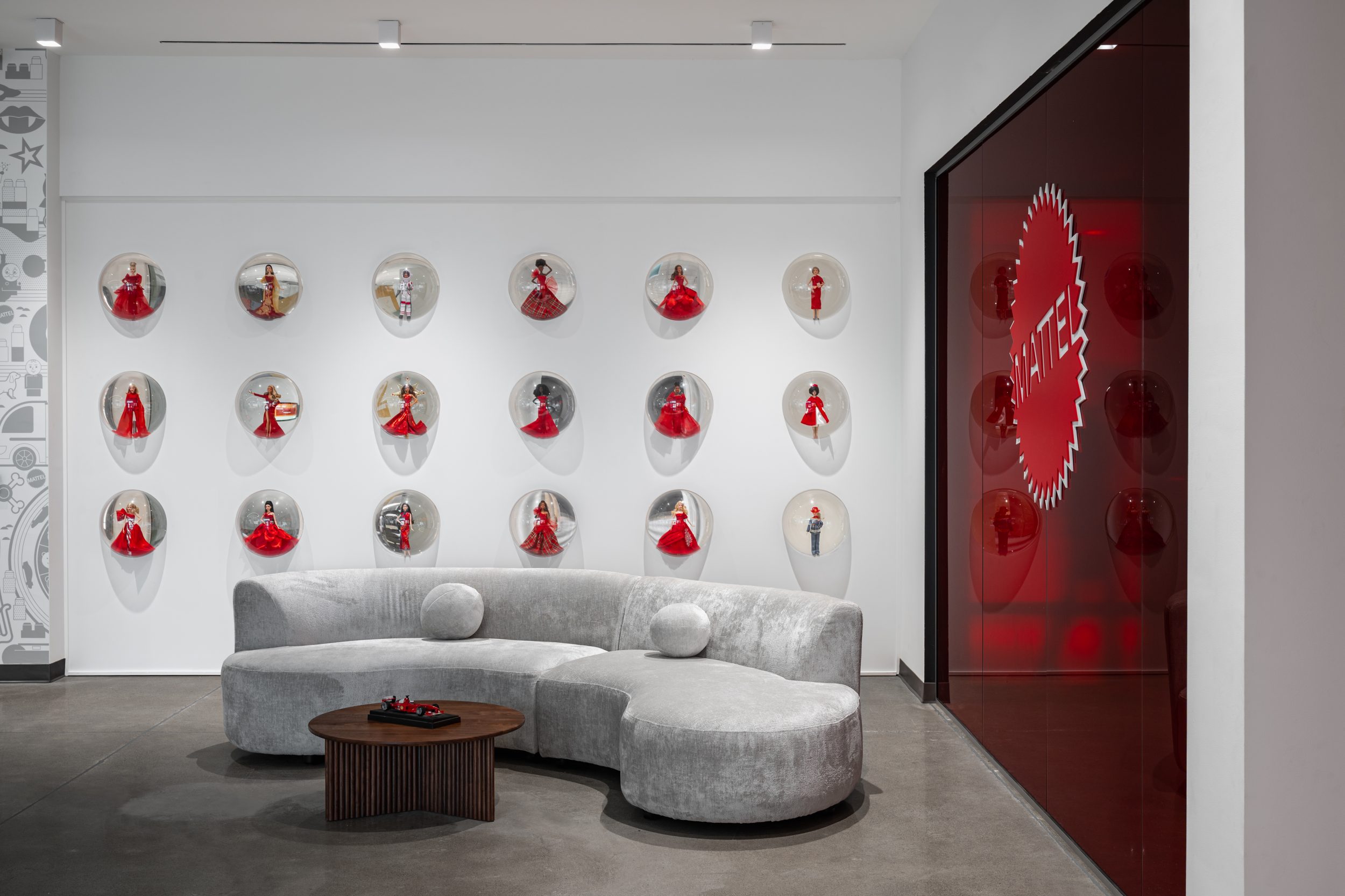 Reception lounge at Mattel Canada Headquarters in Mississauga, Ontario featuring custom lounge furniture, branded feature display wall, premium architectural finishes, commercial office interior design, workplace renovation, and Design-Build corporate headquarters construction completed by GTA General Contractors.