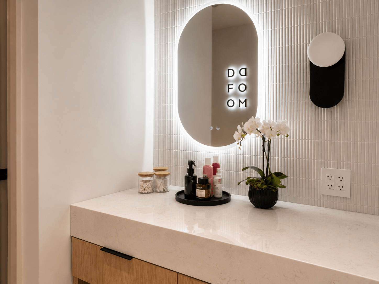 Luxury commercial washroom featuring custom millwork vanity, quartz countertop, illuminated mirror, designer tile wall, premium architectural finishes, and modern wellness facility construction by GTA General Contractors.