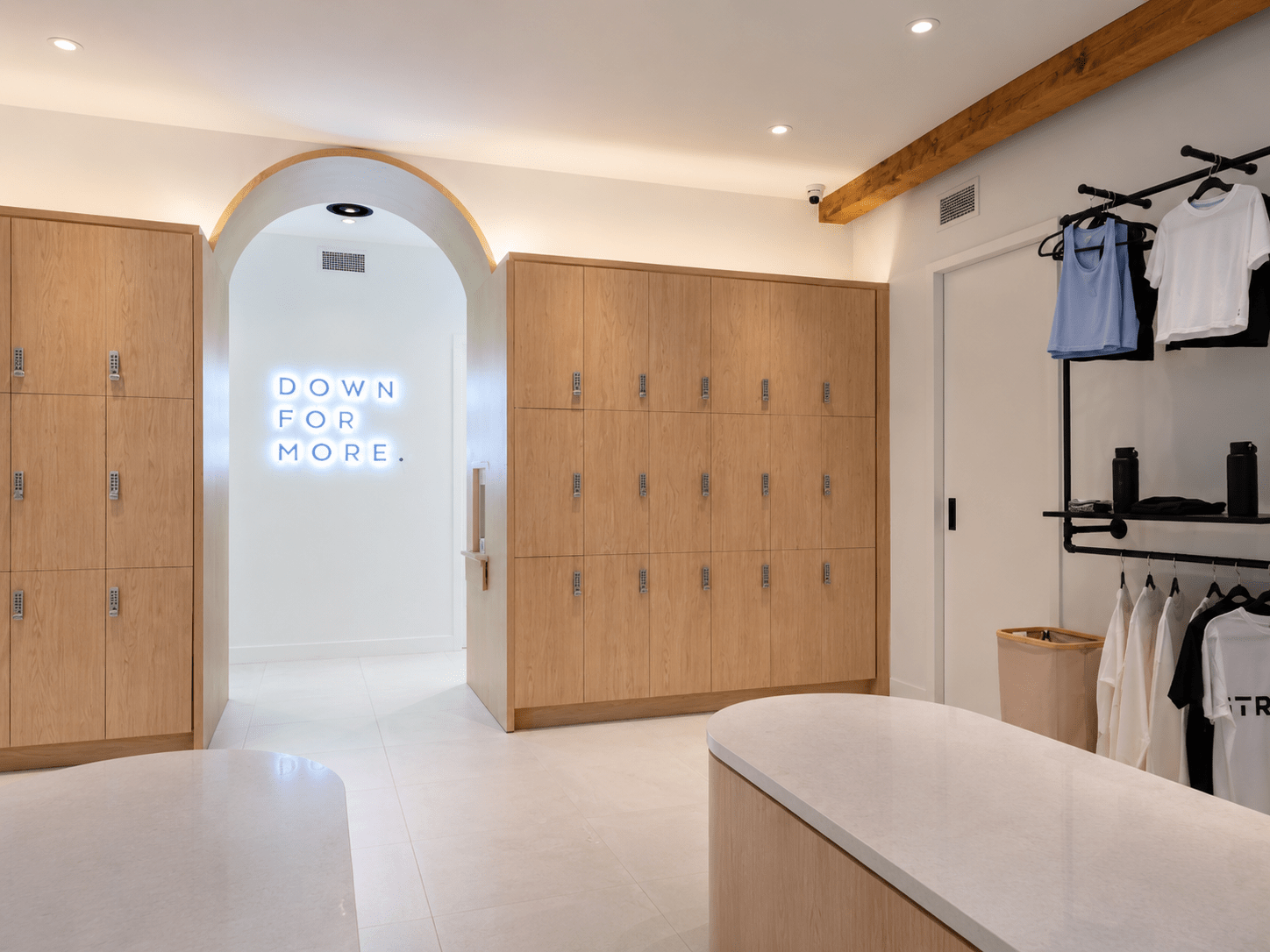 Premium commercial locker room with custom architectural millwork lockers, integrated seating, exposed timber beam, designer lighting, and contemporary wellness facility interior constructed by GTA General Contractors.