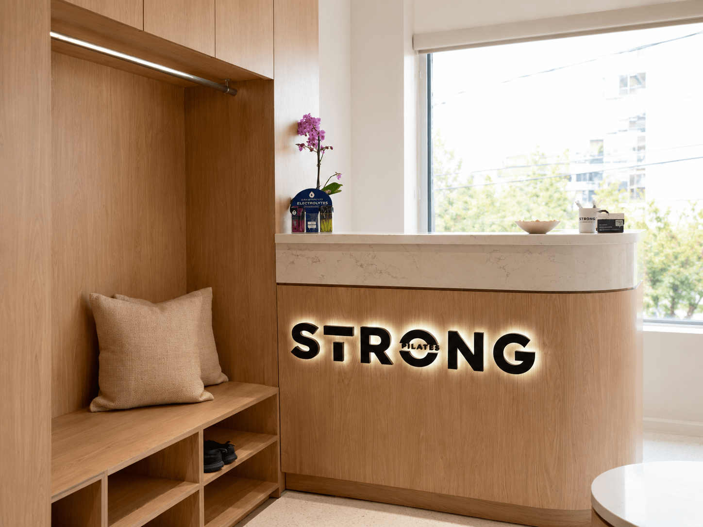 Custom commercial reception desk with architectural millwork, illuminated branding, quartz countertop, integrated storage, premium wood finishes, and modern fitness studio interior construction completed by GTA General Contractors.