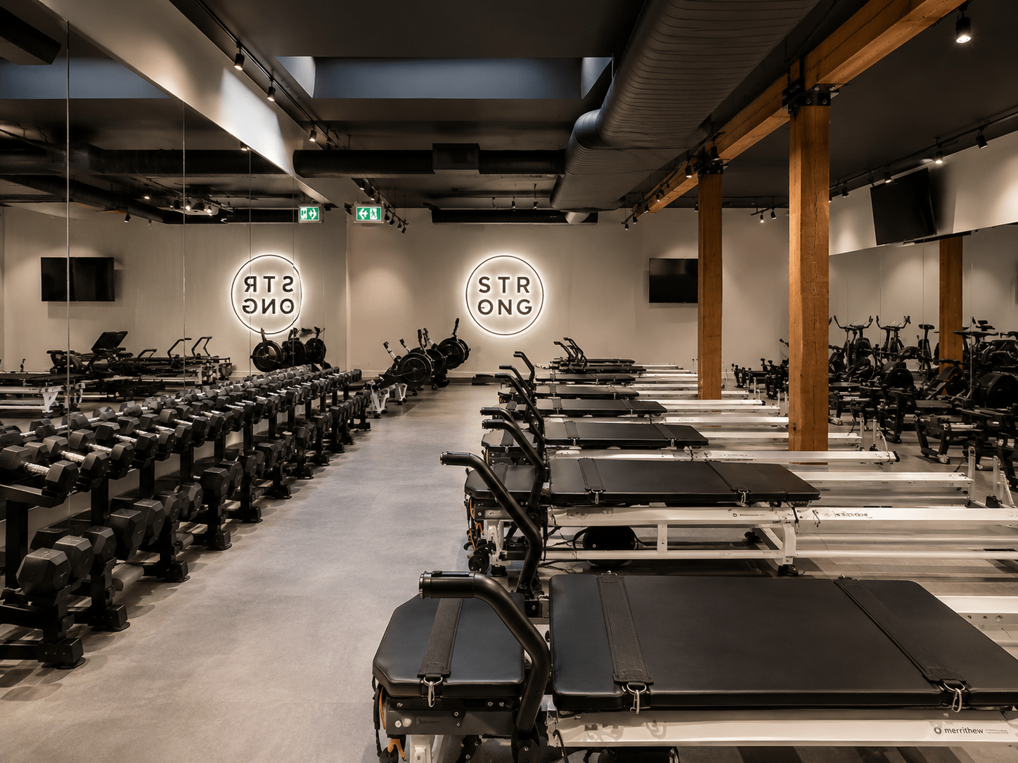 Premium commercial fitness studio constructed by GTA General Contractors featuring custom architectural interiors, Pilates reformer equipment, polished concrete flooring, exposed ceilings, mirrored walls, and modern wellness facility design in Toronto.